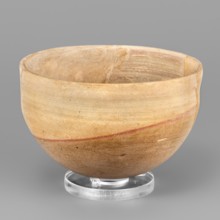 A hemispherical bowl topped with a simple rim, diagonally cut inward. On the outside, below the