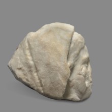 Head of a woman wearing a veil garment. The face is oval, with regular features. The chin is
