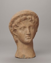 Female votive head, Female head in a wreath, slightly tilted to the right shoulder. Under the