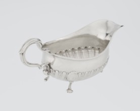 Oval gravy boat, supported on three volute legs, S-shaped handle; wide rim on the axis. Bottom