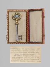 Souvenir key, steel with full shank and a simple feather shaped like two square brackets; gilded