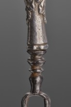 Fork. Two-pronged steel fork with a silver handle shaped as a full-plastic female herm. Unmarked.