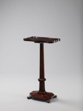 Pedestal table with a rectangular top with a wavy-cut edge and a low wooden gallery, supported by