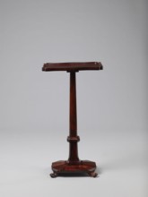 Pedestal table with a rectangular top with a wavy-cut edge and a low wooden gallery, supported by