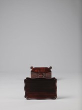 Pedestal table with a rectangular top with a wavy-cut edge and a low wooden gallery, supported by