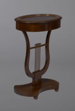 Oval display table with lyre-shaped base mounted on a platform with a concave-convex outline,