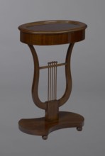Oval display table with a lyre-shaped base mounted on a platform with a concave-convex outline,