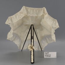 Women's umbrella made of white lace. Its canopy is trimmed with cream silk at the bottom, which