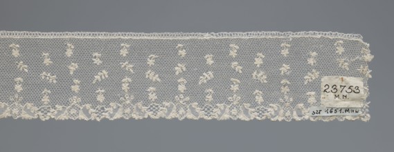 Fragment of lace, one-sided strip of edge ornament made of plant forms with a motif of a pinnately