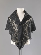 Cape in the form of an elongated rhombus, made of black lace with floral motifs. The edge is