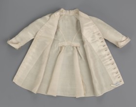 Children's dress made of cream satin. Long, fitted at the top, slightly flared at the bottom.