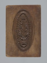 Double-sided gingerbread mould. Obverse: oval frame containing a decorative vase with flowers