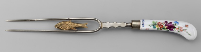 Two-pronged fork with a gilded plastic fish between the tines and a plastic palmette at the base;