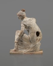 Terracotta figurine of a girl throwing dice. Figurine of a crouching girl throwing dice: weight of