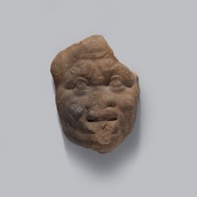 Head of a man. Fragment of a terracotta figurine of a man in a caricatured style. The face is wide
