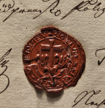 Round wax impression of the seal of the town of Uniejów. A cross standing on a lily, two palm