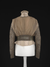 Blouse. Made of beige-gold muslin, short, bloused, fitted at the waist with a belt draped in three