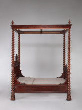 Four-poster double bed with flat pediments topped with a wavy pattern, framed by tall spiral