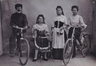 Group portrait of four unknown girls in traditional costume with bicycles, photograph, inscription: