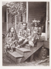 Portrait of a family from Tahiti, sitting on a step in front of the house where they work as