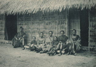 A family sits in front of a house in a recreated Congolese village at the Antwerp World Exhibition