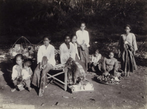 Women and children with goods displayed along the side of the road, Indies women and children with