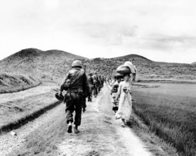 RECORD DATE NOT STATED Korea: During the Korean War (1950-1953), a line of US Army soldiers file past a group of Korean