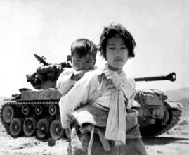 Korea: With her brother on her back a war-weary Korean girl trudges by a M-26 tank at Haengju. Korean War (1950-1953). T