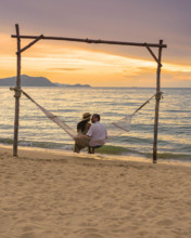 Men and women watching sunset from a hammock on the beach in Pattaya Thailand Ban Amphur beach Men and women are watchin