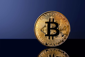 Glänzende Bitcoin-Münze auf reflektierender Oberfläche mit dunkelblauem Hintergrund
