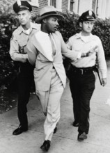 Police officers O.M. Strickland and J.V. Johnson arresting the Reverend Martin Luther King Jr. for loitering near a cou