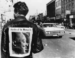 A man wers a placard proclaiming the death of Dr Martin Luther King cut from a local newspaper