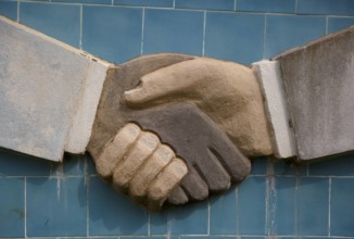Schwarze und weisse Hand reichen sich die Hand. Wandskulptur im Aussenministerium von Benin, Cotonou, 03.01.2016. . Cot