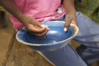 Ein Afrikaner haelt eine leere Schale auf dem Markt von Sokode in seinen Händen, Togo, 05.01.2016. Sokode Togo PUBLICAT