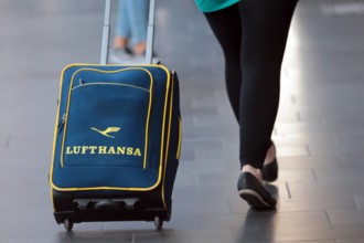 Frau und Rollkoffer mit Lufthansa Logo unterwegs im Hauptbahnhof Frankfurt, Hessen, Deutschland