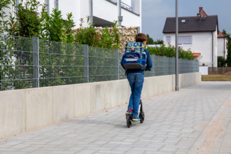 Symbolbild: Schulkind mit Tretroller auf dem Schulweg (model released) *** Symbolic image of a schoolchild with a scoot