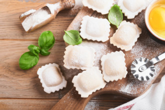Ravioli italienisches Essen. Leckere hausgemachte Pasta Ravioli mit Mehl, Tomaten, Eier und Grüns Basilikum auf hölzernen Hintergrund. Prozess der Herstellung italienischer Ravioli. Lebensmittel Koche...