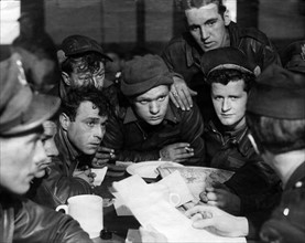 Pilots of the American 8th Air Force being debriefed by an Intelligence Officer following a