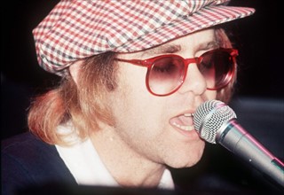 Elton John singing into microphone 
November 1977