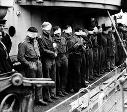 WW2 German prisoners are blindfolded   1943 
as they are brought aboard a British warship after