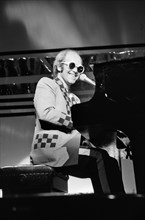 Elton John performing on stage, during the Elton John and Ray Cooper concert tours. Rainbow