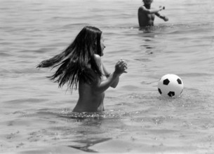 GV Saint-Tropez, France, Tuesday 17th June 1975, topless woman playing with football, in water