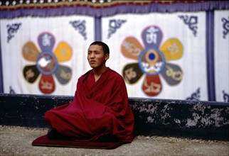 Un moine assis sur le toit du monastère de Jokhong