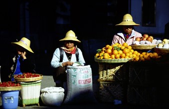 Femmes assises derrière un étal de fruits