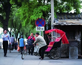 A man earns his living with the traditional pedicab by a hutong of Beijing,China