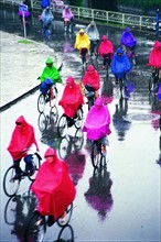 People in raincoat are riding bike across the street of Shenyang,Liaoning Province,China