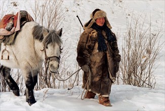 An Oroqen hunter walks with  his horse on the snow in Heilongjiang Province,China