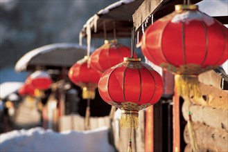 the traditional red lantern for festival hanging outside the snow-covered houses at Shuangfeng Forestry Centre,Mudanjiang,Heilongjiang,China