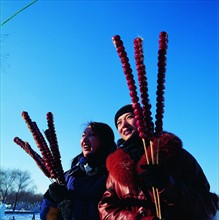 young people holding strings of candied haws,Harbin,China