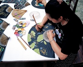 An artist is doing the folk fan painting,Zhejiang,China